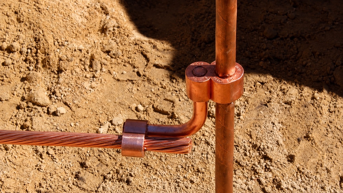 Copper earth rod clamped to a stranded copper conductor in an excavated trench