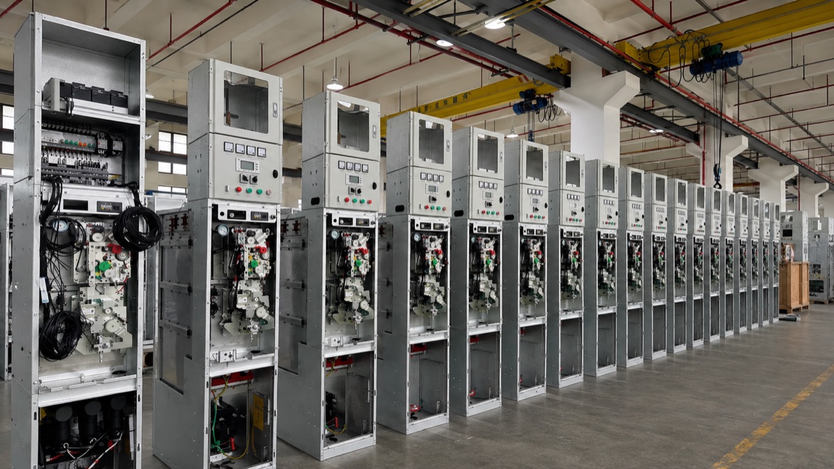 Row of medium-voltage switchgear panels lined up in a factory hall with the front doors open for inspection